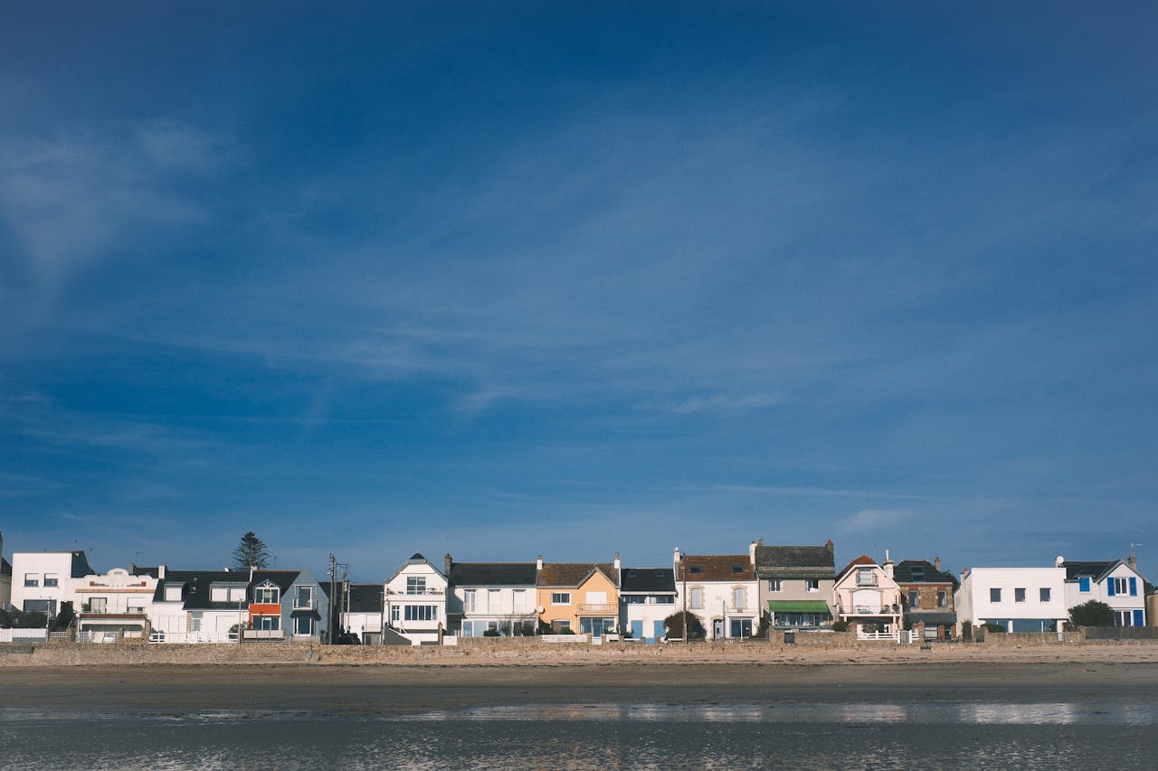 A row of colorful coastal homes by the sea with a blue sky backdrop.